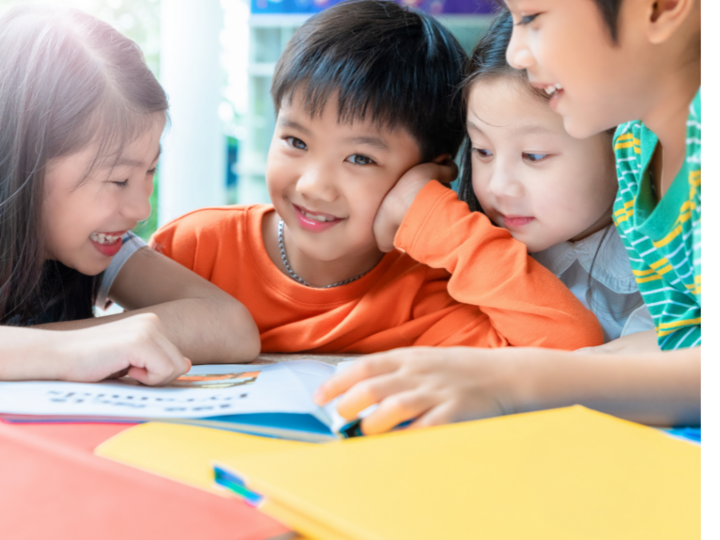 Four children reading a book at the classroom table