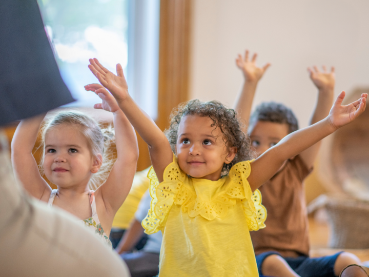 Children gathered together and stretching hands upward to the ceiling