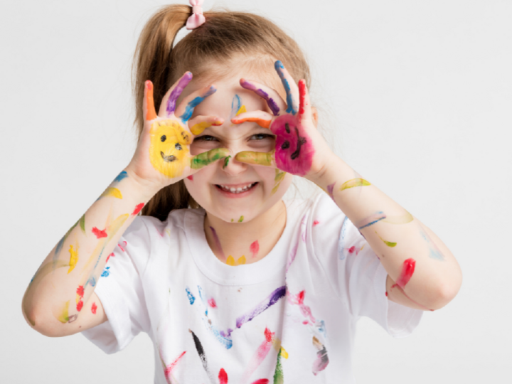 Young girl with finger paint on hands and shirt