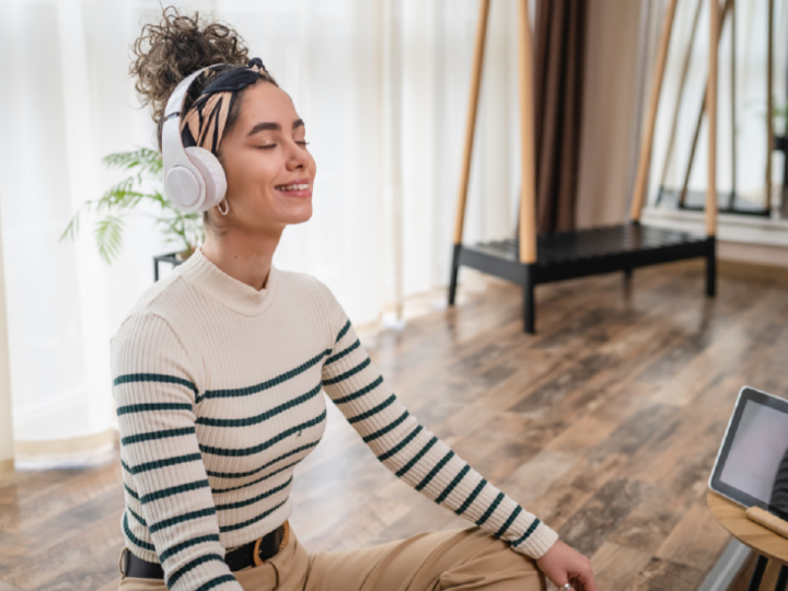 Woman sitting on floor meditating with headphones.