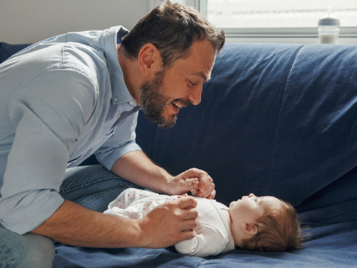 Father talking to baby while sitting on a couch