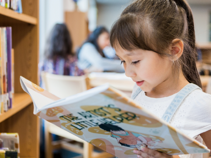Young child reading a storybook in the library
