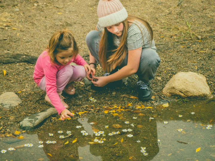 Two children studying pebbles in a river