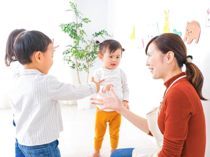 Preschool teacher singing with hands with three young children