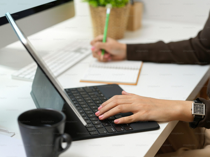 Person working on laptop with a notebook and pen