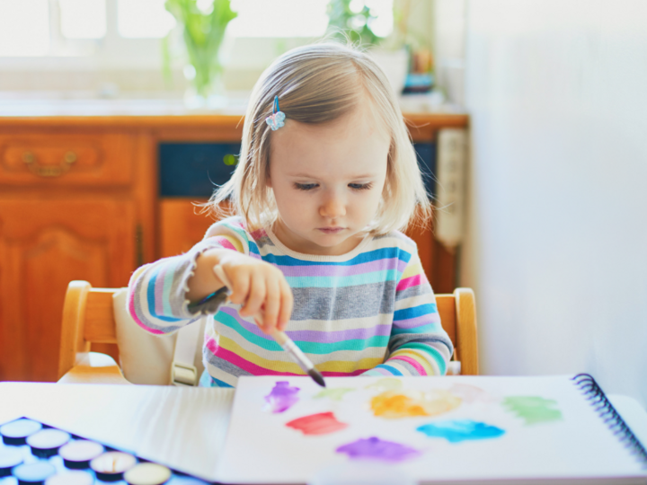 Young girl painting with watercolors at the table