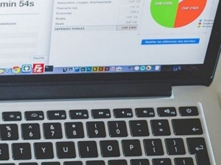 Laptop showing a financial report with graphs and expense details.